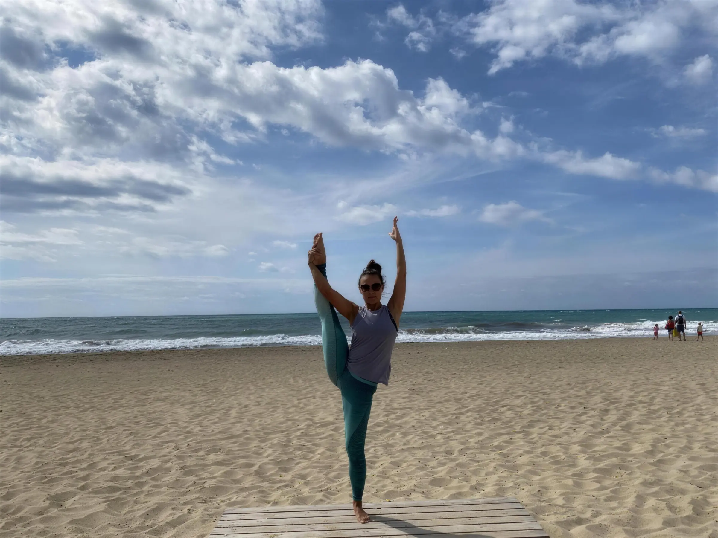 Olga Apryshkina holding a standing split on a beach boardwalk