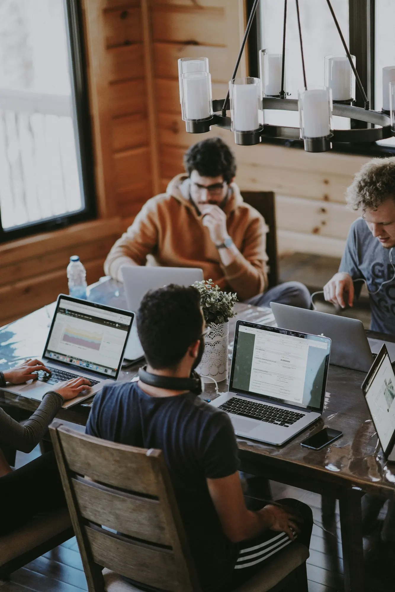 A small team deep in focused work on laptops around a shared wooden table