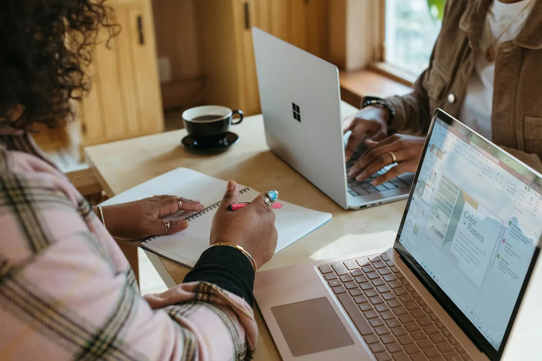 Two members working on laptops in warm light