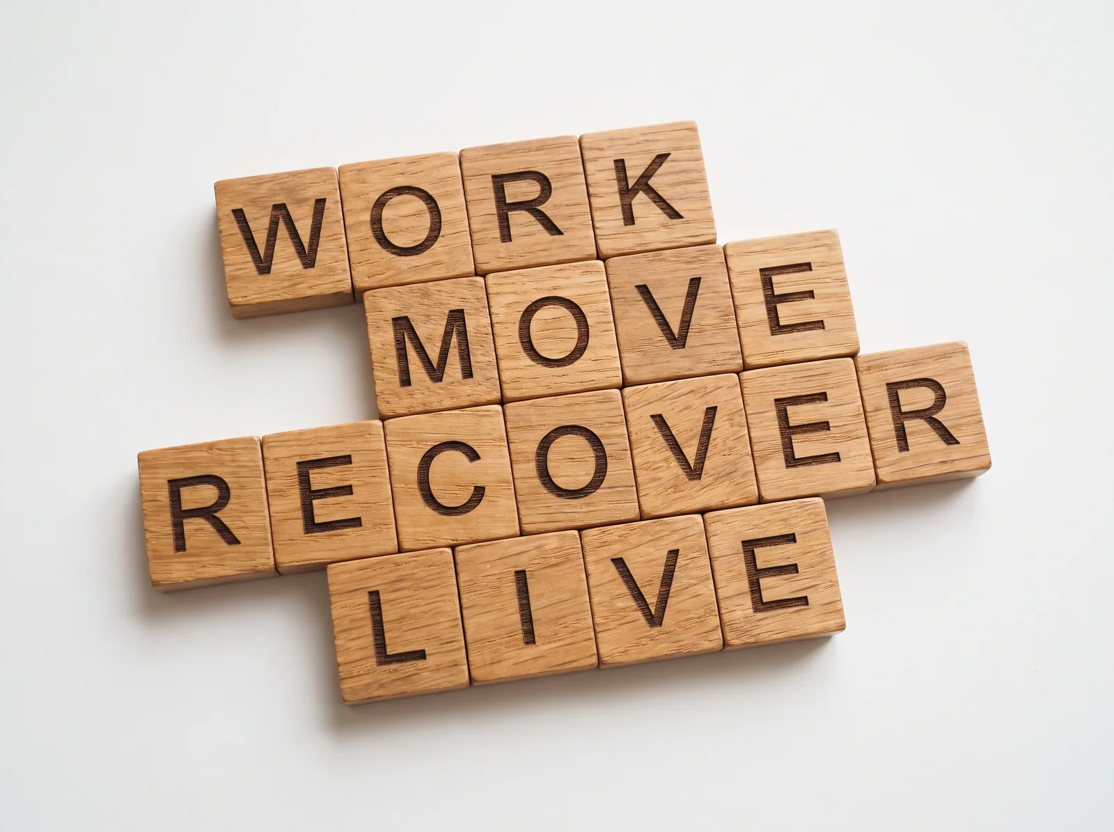 Wooden tiles spelling Work, Move, Recover, Live — the four Thrive Hub pillars
