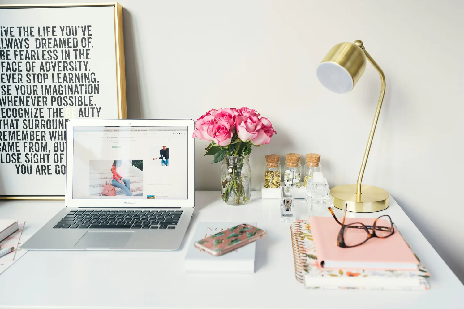 A bright workspace with a laptop, fresh flowers and a desk lamp