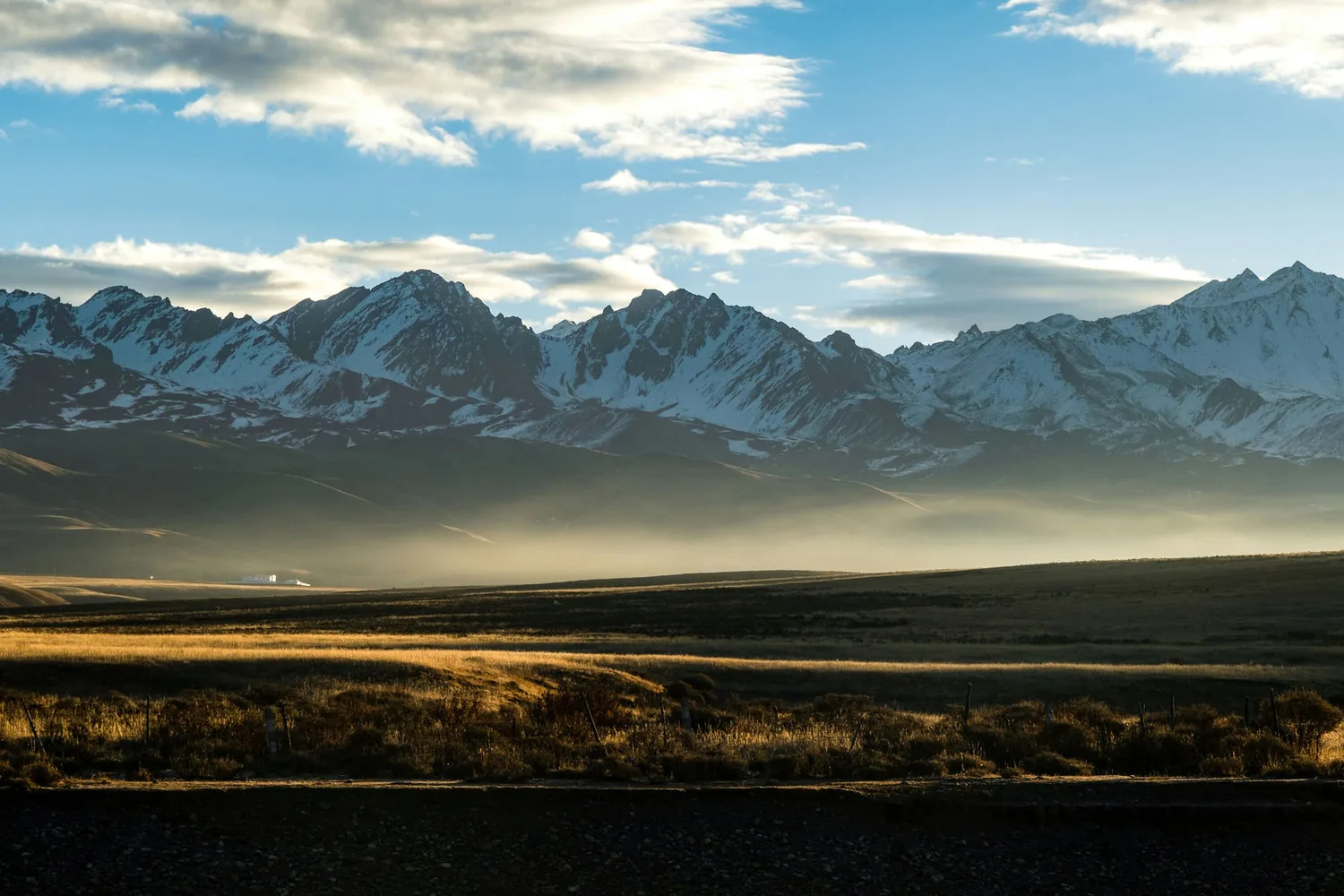 Snow-capped mountain range at golden hour above an open plain