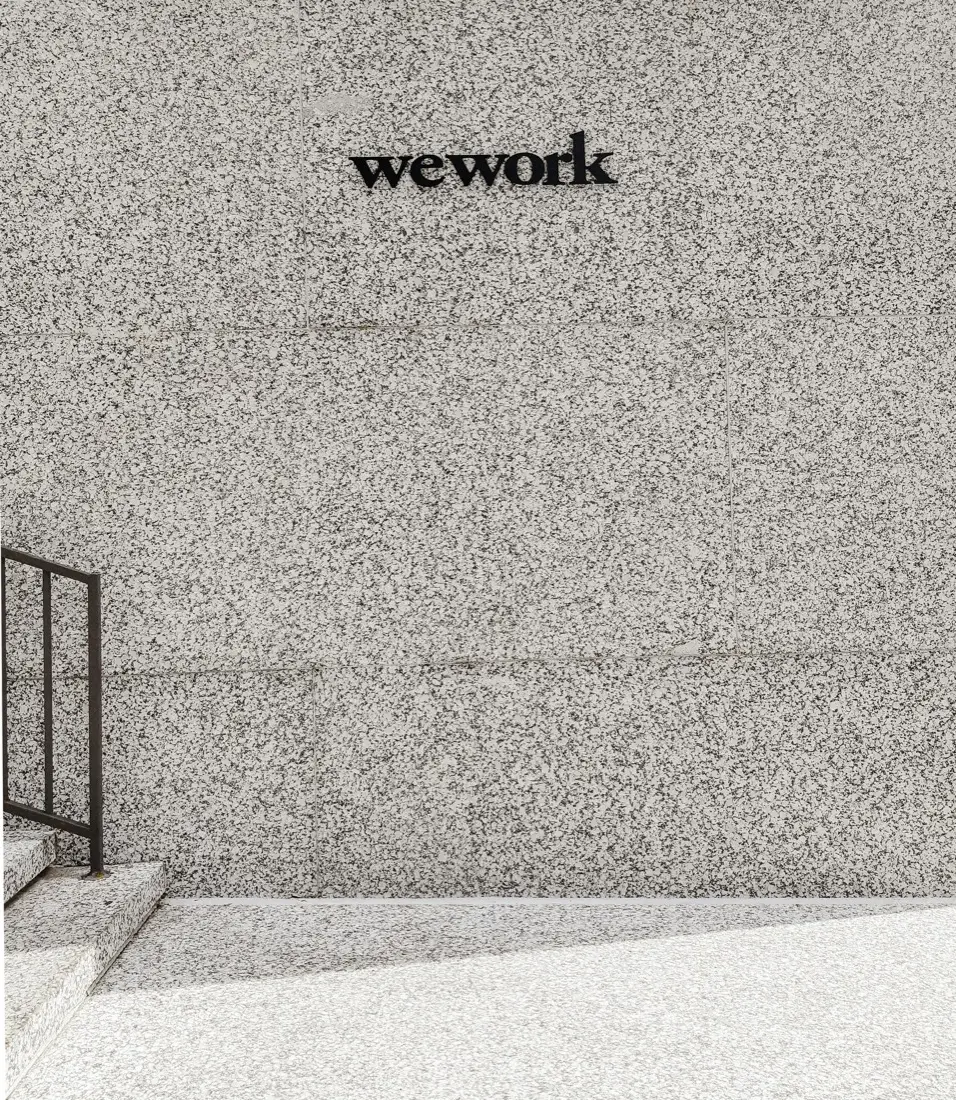 A coworking entrance — black lettering on a speckled granite wall above terrazzo steps